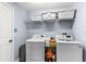 Well-equipped laundry room with modern washer and dryer units and shelving at 15336 Firelight Dr, Winter Garden, FL 34787