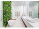 Luxurious bathroom with a freestanding tub, double vanity, and a living wall at 16106 Pendio Dr, Bella Collina, FL 34756