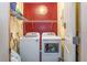 Laundry room featuring a front-loading washer and dryer, shelving, and a bright red wall at 221 Se 125Th Terrace Rd, Silver Springs, FL 34488