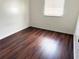 A cozy bedroom with dark wood-look flooring and a window with blinds for natural light at 5123 Picadilly Circus Ct # 2, Orlando, FL 32839
