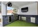 Outdoor kitchen under a covered patio, featuring a built-in grill, television, and artificial turf at 10339 Castillo Ct, Clermont, FL 34711