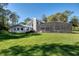 Exterior view of the house highlighting the sprawling green lawn, pool, lanai, and wooded surroundings at 11036 Schooner Way, Windermere, FL 34786