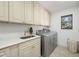 Bright laundry room featuring a utility sink, stone countertops, upper cabinetry, and a front loading washer and dryer at 11036 Schooner Way, Windermere, FL 34786