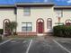 Exterior view of a light beige condo with a red door, landscaping, and parking at 1627 Eagle Creek Cir # 36, Orlando, FL 32807