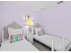 Two twin beds in a lilac-painted bedroom with white-painted furniture and tropical accents at 164 Sevilla Ave, Davenport, FL 33897