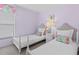 Two twin beds in a lilac-painted bedroom with white-painted furniture and tropical accents at 164 Sevilla Ave, Davenport, FL 33897