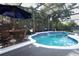Inviting screened pool area with waterfall feature, patio furniture, and lush landscaping at 355 Carriage Way Ct, Oviedo, FL 32765