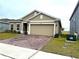 Tan house with two-car garage and brick driveway at 3653 Yarian Dr, Haines City, FL 33844