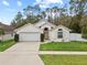 Tan house with white garage door, landscaping, and a white fence at 562 Eagle Pointe S, Kissimmee, FL 34746