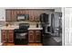 Kitchen features dark wood cabinets and black appliances at 562 Eagle Pointe S, Kissimmee, FL 34746