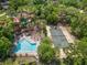 An aerial view of the pool, tennis courts, and homes with a lush tree canopy in the background at 136 Woodmill Rd, Longwood, FL 32779