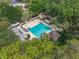 Aerial view of a community pool with a spacious deck, surrounded by lush trees and seating areas at 136 Woodmill Rd, Longwood, FL 32779