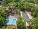 Aerial view of a backyard oasis featuring a pool and tennis court surrounded by lush landscaping and mature trees at 136 Woodmill Rd, Longwood, FL 32779