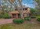 Two-story home featuring a red brick driveway and a two-car garage surrounded by mature landscaping and a red tile roof at 136 Woodmill Rd, Longwood, FL 32779