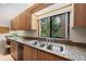 Bright kitchen featuring stainless steel sink, granite countertops, and natural light from window with backyard views at 136 Woodmill Rd, Longwood, FL 32779