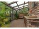 Enclosed patio with brick floor, outdoor kitchen, and plants at 136 Woodmill Rd, Longwood, FL 32779