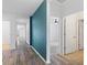 Inviting hallway with wood-look flooring, a teal accent wall, and doorways leading to various rooms at 1504 Finchburg St, Minneola, FL 34715