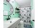 Mint bathroom with white vanity, black accents, and floral shower curtain at 1968 Berkley Rd, Auburndale, FL 33823
