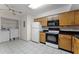 Functional kitchen with wooden cabinets, black countertops, and modern appliances, adjacent to a laundry area at 2923 Marshfield Ct # Ge, Orlando, FL 32822