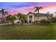 Charming single-story home with a well-manicured lawn and tropical landscaping under a vibrant pink and purple sky at 3181 Winding Trl, Kissimmee, FL 34746