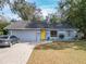 Cute blue house with yellow door, paved driveway, and landscaped yard at 7779 Murcott Cir, Orlando, FL 32835