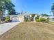 Tan one-story house with a green door, two-car garage, and manicured landscaping at 140 Rangeline Woods Cv, Longwood, FL 32750