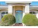 Charming light teal front door with arched entryway and lush landscaping at 140 Rangeline Woods Cv, Longwood, FL 32750