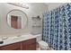 Bright bathroom featuring a round mirror, wood vanity, and blue patterned shower curtain at 1721 Lakelet Loop, Oviedo, FL 32765