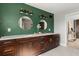 Stylish bathroom featuring a dark green accent wall, double vanity with marble countertop, and round mirrors at 1792 Killarney Dr, Winter Park, FL 32789