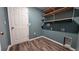 Charming laundry room featuring custom shelving, blue walls, and wood flooring at 2016 West Pkwy, Deland, FL 32724