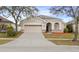 Tan house with a two-car garage and neatly landscaped yard at 2078 Marsh Hawk Dr, Orlando, FL 32837