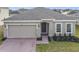 One-story home with gray siding, stone accents, and a two-car garage at 429 Tisone Ln, Davenport, FL 33837