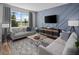 Spacious living room with light gray sofas, a geometric rug, and large windows at 12455 Shipwatch St, Orlando, FL 32832