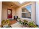 Inviting front porch with terracotta tile, red door, and potted plants at 1849 Dalton Dr, The Villages, FL 32162