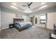 Spacious main bedroom featuring tray ceiling, fan, lake views and gray carpet at 1851 Grand Keahl Ln, Deltona, FL 32738