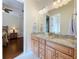 Bathroom featuring double sink vanity with granite countertop, wood cabinets and view to a bedroom at 38207 Sabal Way, Umatilla, FL 32784