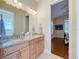 Bathroom featuring double sink vanity with granite countertop, wood cabinets and view to a bedroom at 38207 Sabal Way, Umatilla, FL 32784