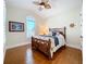 Bright bedroom with decorative ceiling fan, wood floors, and a large decorative wood bed frame at 38207 Sabal Way, Umatilla, FL 32784