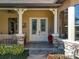 Inviting front porch with glass paneled doors, stone accents, and decorative plants at 38207 Sabal Way, Umatilla, FL 32784