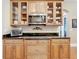 Kitchen featuring wood cabinets with glass doors, stainless steel microwave, and dark countertops at 38207 Sabal Way, Umatilla, FL 32784