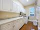 Bright laundry room with white cabinets, counters, utility sink, and modern appliances at 38207 Sabal Way, Umatilla, FL 32784