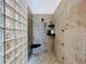 Modern shower featuring stone tiling, glass block partition and corner seat at 38207 Sabal Way, Umatilla, FL 32784