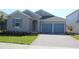 Gray house with blue doors and a paved driveway at 4476 Lions Gate Ave, Clermont, FL 34711