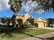 Beautiful tan house with a two-car garage, palm trees, and nicely landscaped yard at 6879 Remington View Ct, Orlando, FL 32829