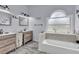 Elegant bathroom featuring double sinks, a soaking tub, and a large arched window at 752 Americana Ct, Kissimmee, FL 34758