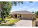 Lovely single-Gathering home showcasing a lush front lawn, mature trees, and a brick-paved driveway at 1569 Victoria Way, Winter Garden, FL 34787