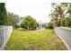 Expansive backyard featuring mature trees, lush greenery, a white fence, and a screened-in porch area at 2225 Kettle Dr, Orlando, FL 32835