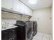 Laundry room with modern washer and dryer units and upper cabinets for storage at 2225 Kettle Dr, Orlando, FL 32835