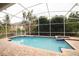 Beautiful screened-in pool with a spa, surrounded by lush landscaping and a brick patio at 2225 Kettle Dr, Orlando, FL 32835