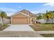 Tan two-story house with a red door, two palm trees, and a driveway at 2267 Santa Lucia St, Kissimmee, FL 34743